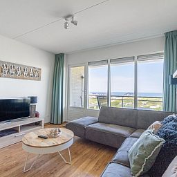 Geraeumiges Wohnzimmer des Appartements Juliana 102 Zeezicht, De Koog, Texel mit moderner Einrichtung und Meerblick.