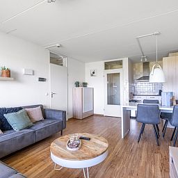 Gemuetliches Wohn- und Esszimmer im Appartement Juliana 102 Zeezicht, De Koog, Texel mit Zugang zur Kueche.