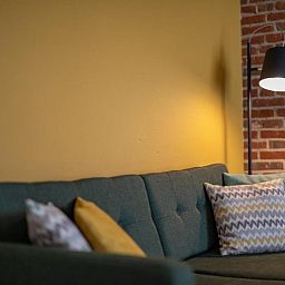 Gemuetliches Sofa mit Kissen im Apartment 4 bis 6 Personen, De Koog, Texel, bietet eine warme Atmosphaere fuer Ihren Aufenthalt.