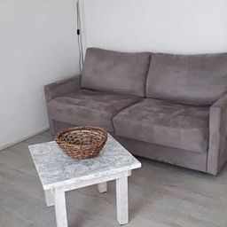 Comfortable sitting area in Apartment Dorpsstraat 245 in De Koog, Texel with gray sofa.