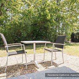 Sunny terrace at Type 4 vacation home, De Koog, Texel. Perfect for outdoor dining amidst nature.