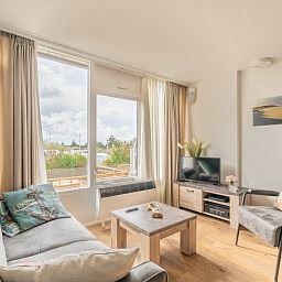 Helles Wohnzimmer des Appartements Juliana 076 Eilandzicht in De Koog, Texel, mit bequemen Sitzmoebeln und moderner Einrichtung.