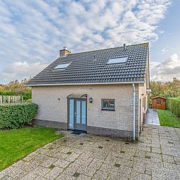 Front view of Stappeland 197, a vacation home in De Koog, Texel with stone facade and garden.