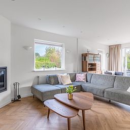 Spacious living room in Stappeland 197, vacation home De Koog, Texel with corner sofa and garden view.