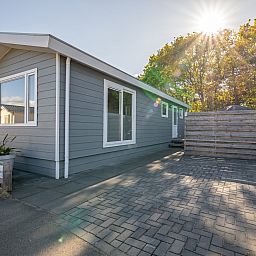 Sunny front view of Chalet Bregkoog 12, a vacation home in De Koog, Texel, ideal for a relaxing stay.