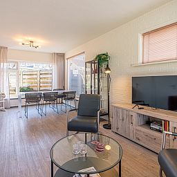Helles Wohnzimmer des Ferienhauses De Zandduyn in De Koog, Texel, mit modernen Moebeln und TV.