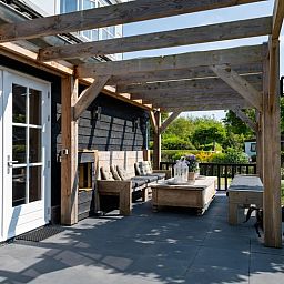 Veranda van vakantiehuis Residence Rustiek in De Koog, Texel met houten meubels.