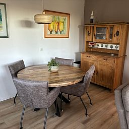 Dining area in Stormvogel, vacation home in De Koog, Texel with round table and wooden cabinet.