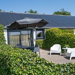 Cozy terrace with seating at Bungalow 2, vacation home in De Koog, Texel, surrounded by greenery.