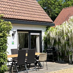 Terrace of Koetshuis 3 vacation home in De Koog, Texel with dining table and green planting.