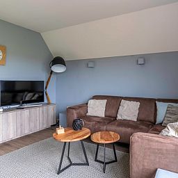 Gemuetliches Wohnzimmer im Ferienhaus in De Waal, Texel mit bequemem Sofa und moderner Einrichtung fuer einen entspannten Urlaub.
