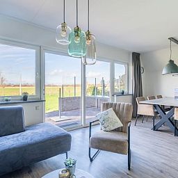 Helles Wohnzimmer im Ferienhaus in De Waal, Texel mit grossen Fenstern und schoener Aussicht auf die Natur von Texel.