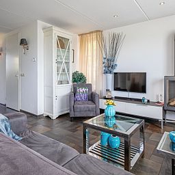 Gemuetliches Wohnzimmer in der Villa Magnifique, Den Burg, Texel: modern eingerichtet mit Kamin und Fernseher.