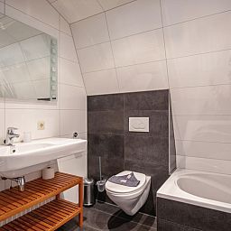 Luxurioeses Badezimmer in der Villa Magnifique, Den Burg, Texel: stilvolle Einrichtung mit Badewanne und modernem Waschbecken.