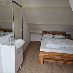 Attraktives Schlafzimmer im Ferienhaus Kogerstraat, Den Burg, Texel. Geraeumiges Doppelbett unter einer Dachschraege fuer Ruhe und Komfort.