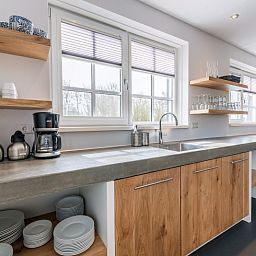 Moderne Kueche in der Gruppenunterkunft Nieuw Leven 36p, Ferienhaus Texel, mit Holzschraenken und grosszuegigen Arbeitsflaechen.