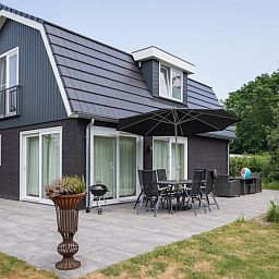 Modern exterior of Villa 3C in Den Burg, Texel, with cozy sitting area on the terrace, ideal vacation home.