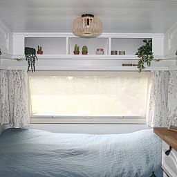 Schlafbereich im Caravan Rust & Ruimte, Den Hoorn, Texel, mit grossem Fenster und gemuetlicher Einrichtung.