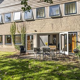 Aussenterrasse des Ferienhauses Sil in Den Hoorn, Texel mit Gartenmoebeln und gruener Umgebung.