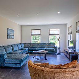 Gezellige woonkamer in vakantiehuis 46 - Nieuw Zeeland, Oosterend, Texel, met comfortabele zitbank.