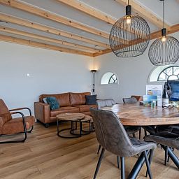 Gemuetliches Wohnzimmer im Cottage in Oudeschild, Texel, mit Holzbalken und komfortablen Moebeln.