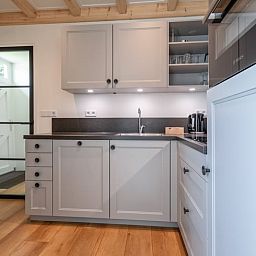 Moderne Kueche im Ferienhaus in Oudeschild, Texel, mit stilvollen Schraenken und Geraeten.