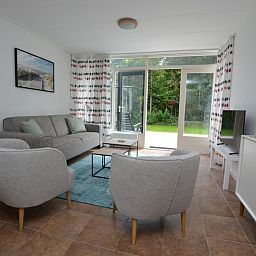 Gemuetliches Wohnzimmer des Ferienhauses de Parel 182 in De Dennen, Texel mit Blick auf den Garten.