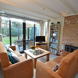 Gezellige woonkamer in Vakantiehuis de Parel 212, De Dennen, Texel met uitzicht op groene omgeving.