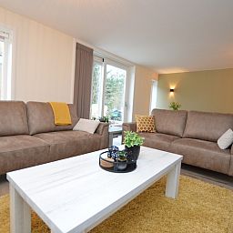 Gemuetliches Wohnzimmer des Ferienhauses De Nagtegaal 23, De Dennen, Texel, mit viel Tageslicht.