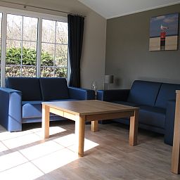 Helles Wohnzimmer von Villetta Sauna, Texel, mit bequemen Sofas und Blick auf die Natur.