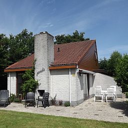 Aussenansicht des Ferienhauses Gortersmient 330, De Dennen, Texel mit Terrassenstuehlen.