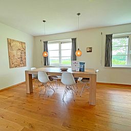 Eetkamer in Appartement Bos en Duin 40, De Dennen, Texel, met grote houten tafel en ramen met uitzicht op de natuur.