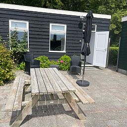 Terrace of Wollewei vacation home in De Dennen, Texel, with wooden picnic table and chairs.