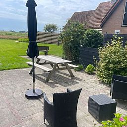 View from the terrace of Wollewei vacation home in De Dennen, Texel, with green garden.