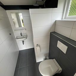Modern bathroom in vacation home Wollewei, De Dennen, Texel, with toilet and sink.