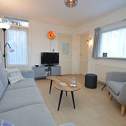 Moderne Sitzecke im Bungalow Uterste Coogh 104, De Dennen, Texel, mit Fernseher und dekorativen Elementen.