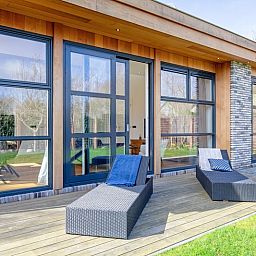 Luxe ligstoelen op het terras van Vakantiehuis De Vlinder in Bungalowpark 't Hoogelandt, De Dennen, Texel, met uitzicht op de tuin.