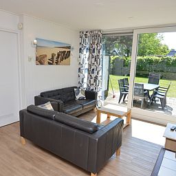 Helle Innenraeume im Ferienhaus de Parel 282, De Dennen, Texel mit gemuetlicher Sitzecke und Gartenblick.