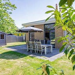 Bungalowpark Verste Coogh - Hermelijn, Texel: Geraeumige Terrasse mit Sitzgelegenheiten in gruener Umgebung.
