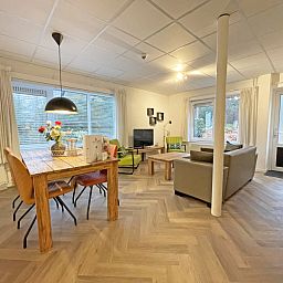Bright and spacious dining room in Apartment Bos en Duin 04, De Dennen, Texel with wooden table and modern chairs.