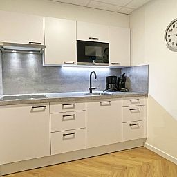 Modern kitchen in Apartment Bos en Duin 04, De Dennen, Texel with sleek white cabinets and built-in appliances.
