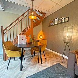 Essbereich im Appartement Bos en Duin 24, De Dennen, Texel mit Holztreppe und gemuetlicher Beleuchtung fuer stimmungsvolles Essen.