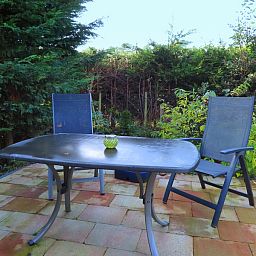 Ruhige Terrasse des Ferienhauses Dunkonijn, De Dennen, Texel, umgeben von gruener Natur.