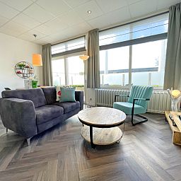 Bright living room of Apartment Bos en Duin 02, Texel, with large windows and an inviting seating area.