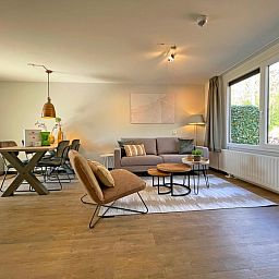 Geraeumiges Wohnzimmer im Apartment Bos en Duin 09, De Dennen, Texel mit Essecke und Blick auf die Natur.