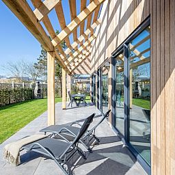 Ontspannen op het terras van Bungalowpark 't Luwe Land - Nieuw Vredelust, Texel. Comfortabele ligstoelen en natuurlijke omgeving.