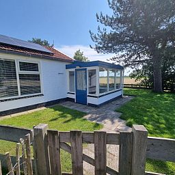 Entrance of Weidezicht vacation home in De Dennen, Texel with garden and green surroundings.