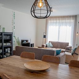 Esszimmer und Wohnzimmer im Ferienhaus 't Hoogelandt 136, De Dennen, Texel, mit Kamin und modernen Moebeln.