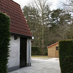 Seitenansicht des von gruenen Hecken umgebenen Ferienhauses Gortersmient 354 in De Dennen Texel.