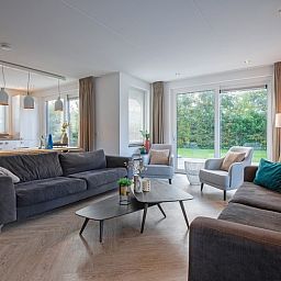 Stilvolles Wohnzimmer der Villa Bloem en Bos in De Dennen, Texel, mit bequemen Sofas und viel Tageslicht.